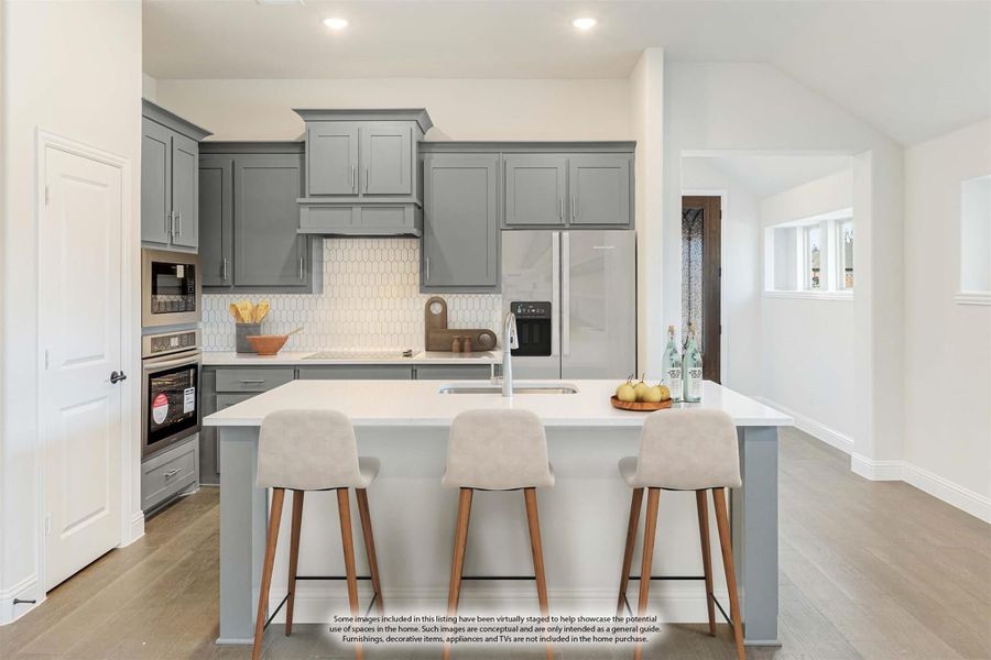 Kitchen with gray cabinets, white tile backsplash, center island with three bar stools, and stainless steel appliances
