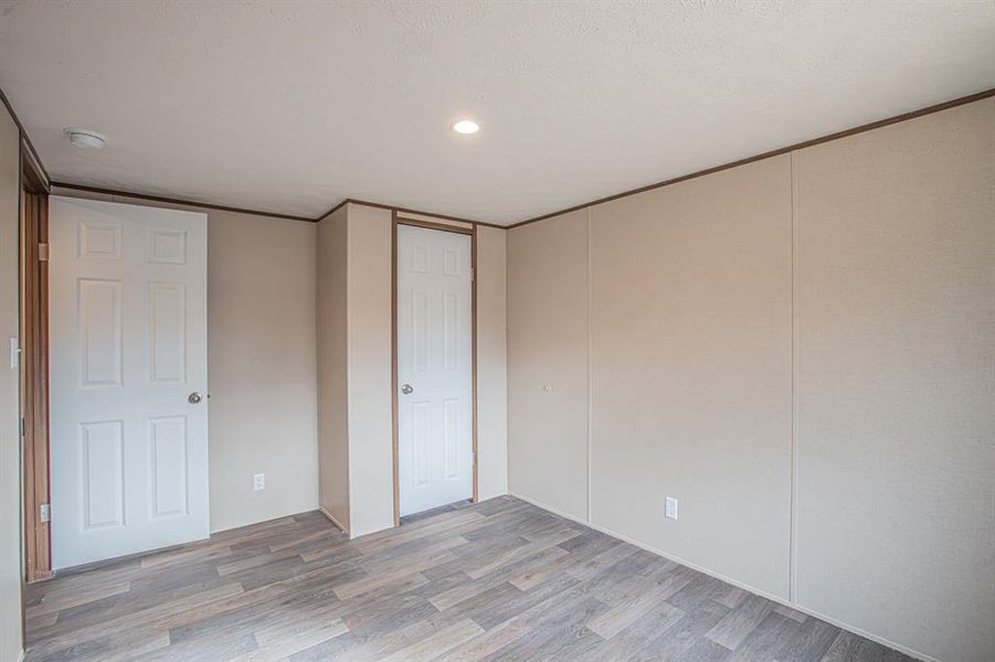 Unfurnished bedroom with light hardwood / wood-style floors and ornamental molding Unfurnished bedroom with light hardwood / wood-style floors and ornamental molding