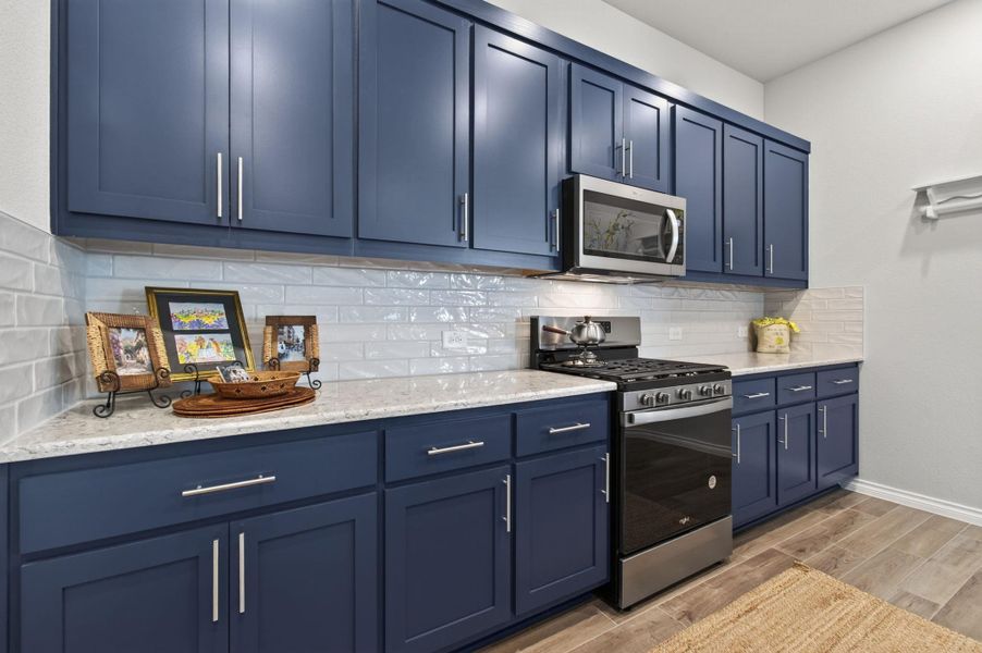 A well-appointed kitchen features rich blue cabinetry, granite countertops, and modern stainless steel appliances. A well-appointed kitchen features rich blue cabinetry, granite countertops, and modern stainless steel appliances.