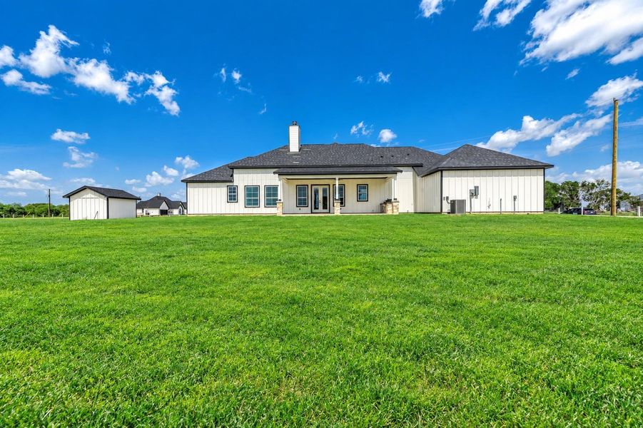 Rear view of the home featuring a covered patio and a spacious backyard with plenty of room for outdoor living. Rear view of the home featuring a covered patio and a spacious backyard with plenty of room for outdoor living.