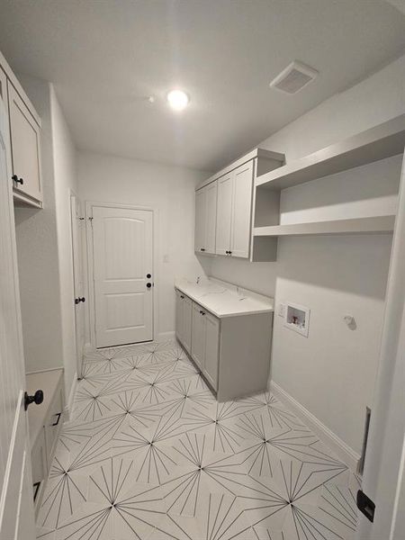Washroom with cabinet space, washer hookup, and light tile patterned flooring