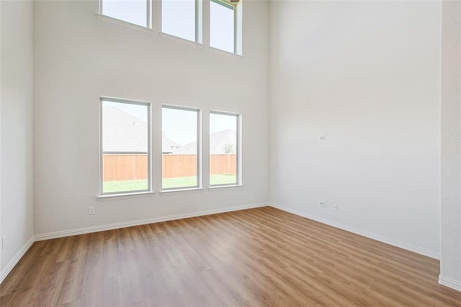 Empty room featuring light wood-type flooring and a towering ceiling