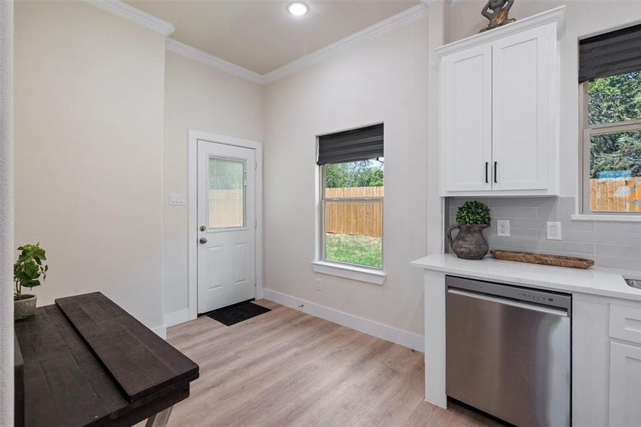 Kitchen featuring dishwasher, tasteful backsplash, white cabinets, and light wood-style floors