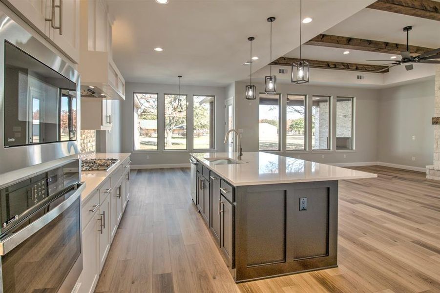 Kitchen with beamed ceiling, appliances with stainless steel finishes, white cabinetry, and sink