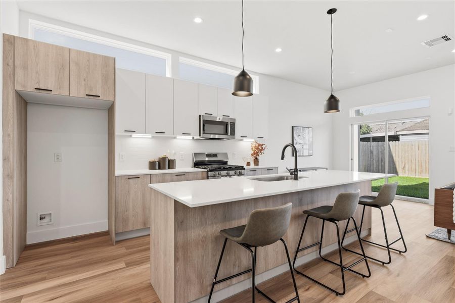 A clean backsplash, soft under-cabinet lighting, and pendant lighting that anchors the island.