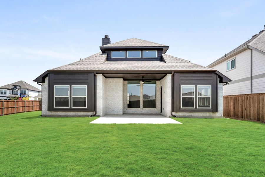 Rear exterior of single-story home with white brick, dark siding, covered patio, and large fenced backyard Rear exterior of single-story home with white brick, dark siding, covered patio, and large fenced backyard