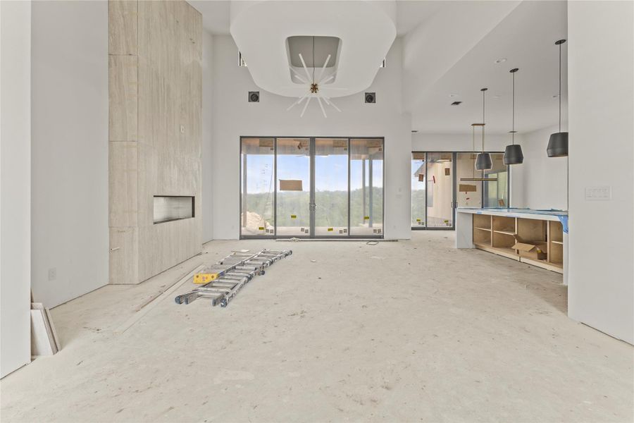 Spacious interior featuring high ceilings, a linear fireplace with a stone surround, and large sliding glass doors