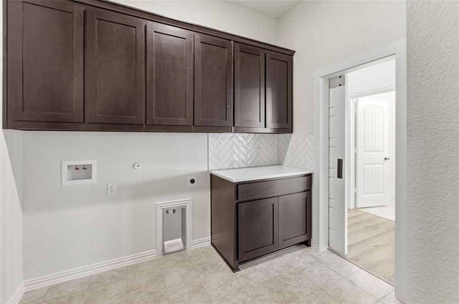 Laundry area featuring hookup for an electric dryer, cabinet space, gas dryer hookup, hookup for a washing machine, and light tile patterned flooring