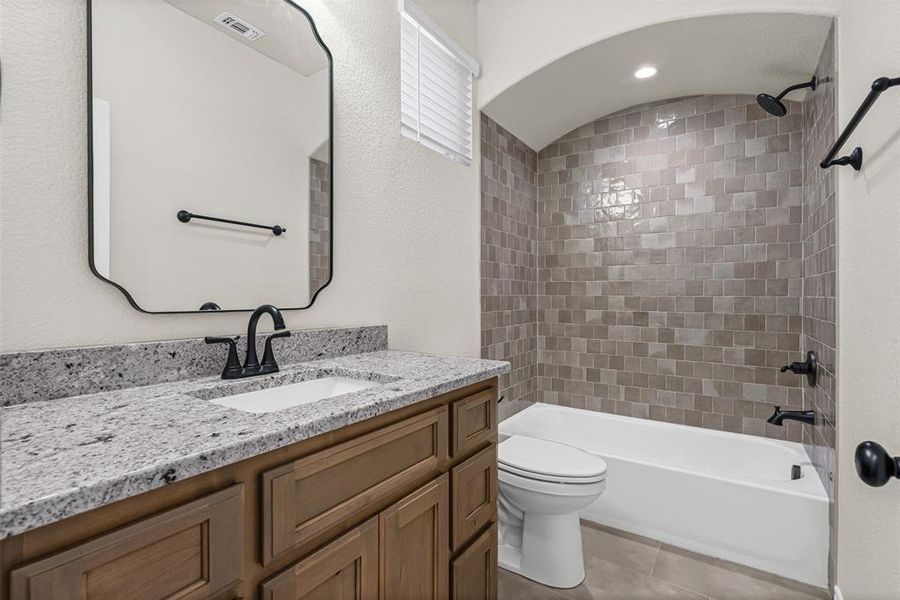 Full bath featuring tub / shower combination, vanity, and light tile patterned floors