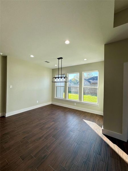 Bright dining area with large windows overlooking a fenced backyard. Features wood-look tile flooring and a modern light fixture, creating a warm, inviting space. Bright dining area with large windows overlooking a fenced backyard. Features wood-look tile flooring and a modern light fixture, creating a warm, inviting space.