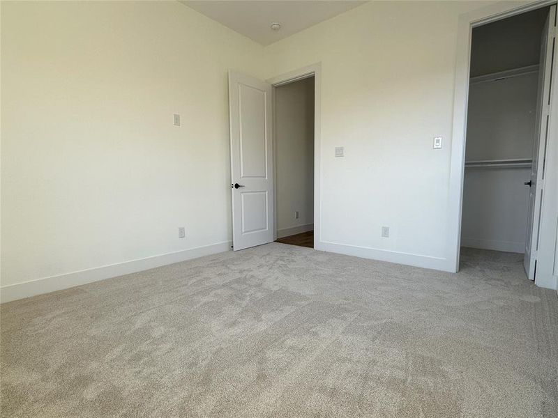 Unfurnished bedroom featuring a walk in closet, a closet, and carpet flooring