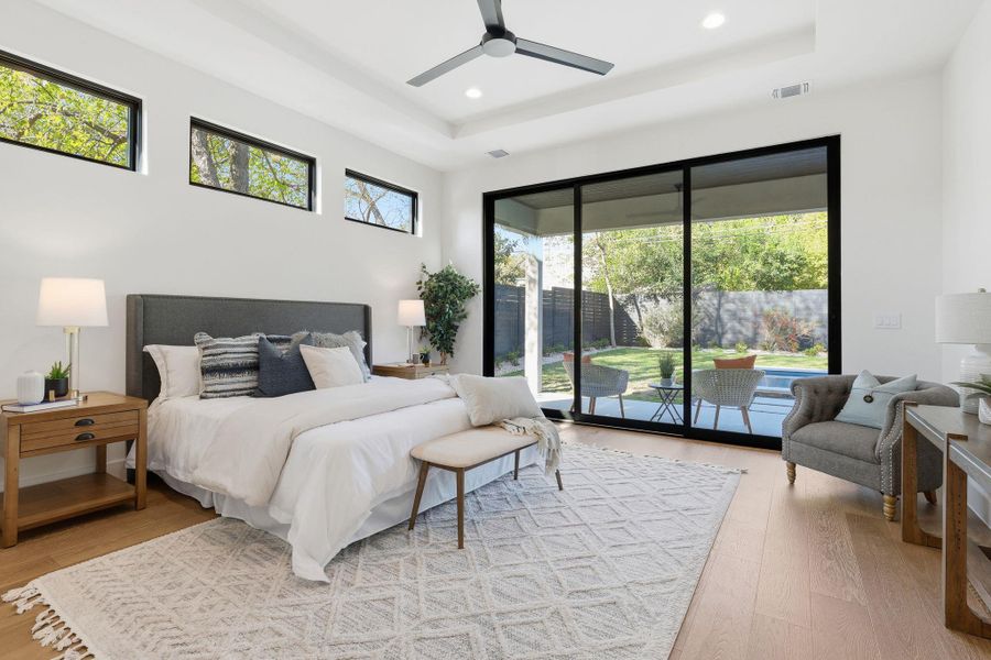 Bedroom featuring light wood-style floors, access to exterior, a ceiling fan, recessed lighting, and a raised ceiling Bedroom featuring light wood-style floors, access to exterior, a ceiling fan, recessed lighting, and a raised ceiling