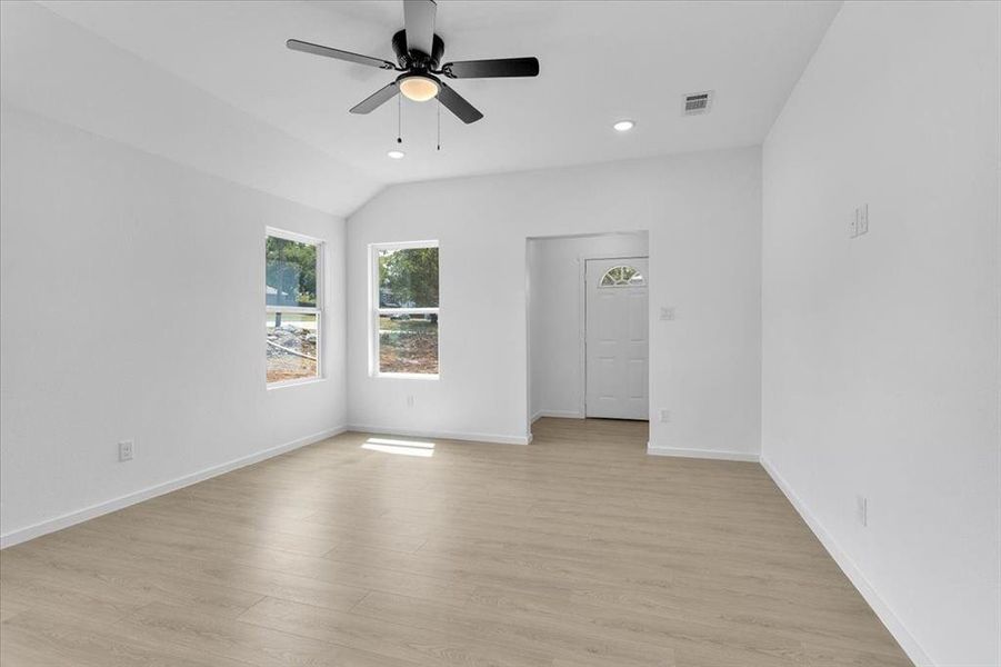 Unfurnished room with ceiling fan, light wood-type flooring, and lofted ceiling