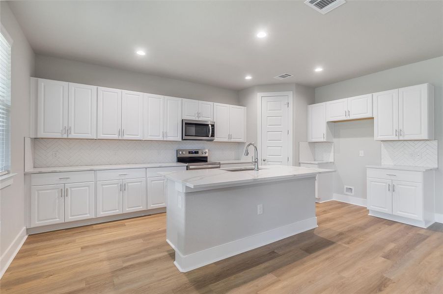 Modern white kitchen with natural lighting, quartz countertops, sleek cabinetry, stainless appliances, recessed lighting, large center island, pantry, and modern backsplash design. Modern white kitchen with natural lighting, quartz countertops, sleek cabinetry, stainless appliances, recessed lighting, large center island, pantry, and modern backsplash design.