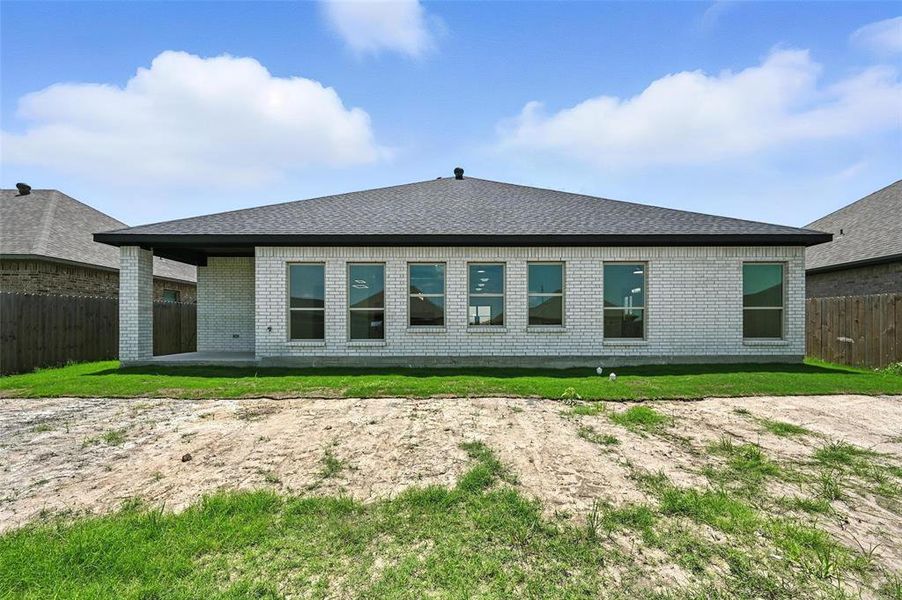 Rear view of house featuring brick siding, a shingled roof, and a patio