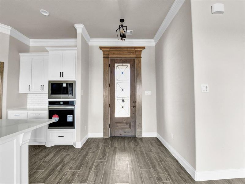 Kitchen featuring built in microwave, white cabinets, crown molding, and oven Kitchen featuring built in microwave, white cabinets, crown molding, and oven