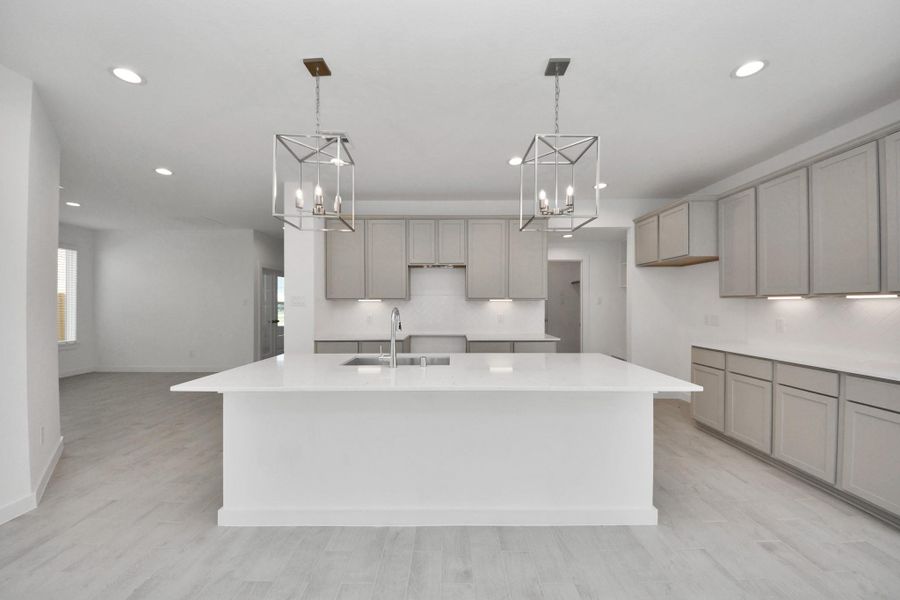 The kitchen is a culinary haven, featuring granite countertops, a tile backsplash, stainless steel appliances, 42” upper cabinets, and undercabinet lighting. Sample photo of completed home with similar floor plan. Actual colors and selections may vary.