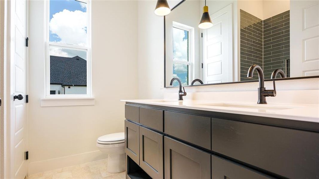 Bathroom featuring a healthy amount of sunlight, double sink vanity, toilet, and tile floors