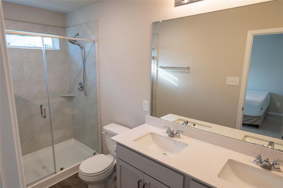 Primary bathroom with double vanity, designer fixtures, and spa-like shower.