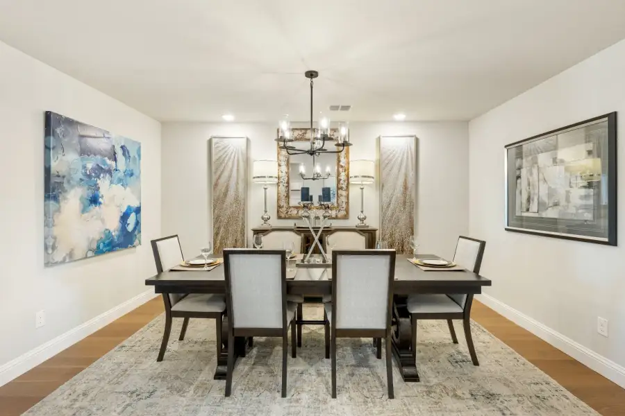Formal dining room with dark wood table, six upholstered chairs, chandelier, and hardwood floors