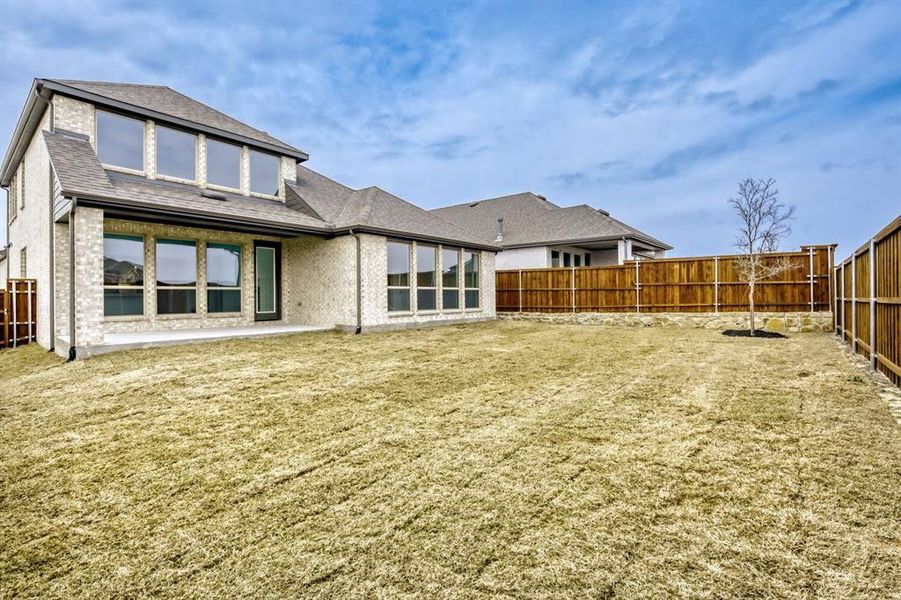 Rear view of house with a fenced backyard, brick siding, a patio area, and a shingled roof