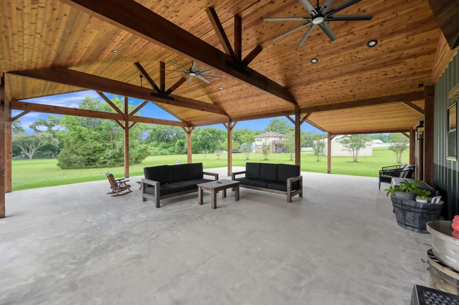 spacious, covered outdoor patio with natural wood beams and ceiling, featuring ceiling fans