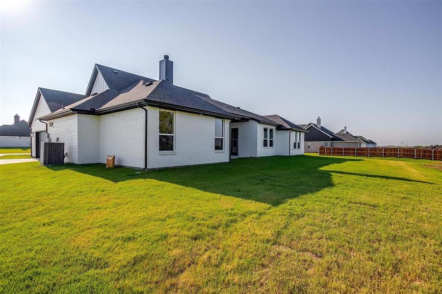 Rear view of property with a lawn and cooling unit