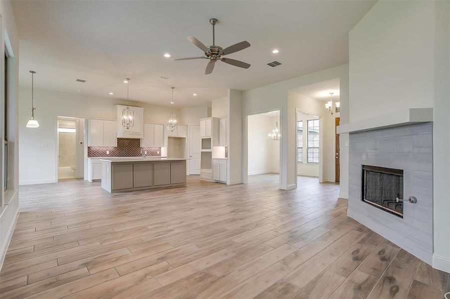 Unfurnished living room with a fireplace, ceiling fan, and light wood-type flooring