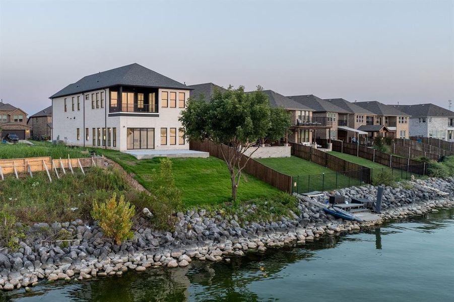 Rear view of property featuring a water view, a residential view, a patio, a fenced backyard, and a balcony