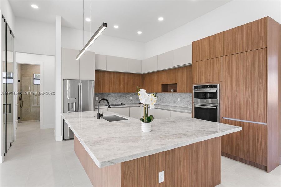 The CHEF'S KITCHEN offers OVERSIZED L-SHAPED ISLAND w/ MARBLE COUNTERTOP & extra entertainment space! Custom cabinetry, MARBLE TAJ MAHAL COUNTERTOPS w/ FULL BACKSPLASH, large pantry & premium GE appliances including wall oven, microwave, electric cooktop, dishwasher, refrigerator and freezer, plus a large sink with black fixtures. The CHEF'S KITCHEN offers OVERSIZED L-SHAPED ISLAND w/ MARBLE COUNTERTOP & extra entertainment space! Custom cabinetry, MARBLE TAJ MAHAL COUNTERTOPS w/ FULL BACKSPLASH, large pantry & premium GE appliances including wall oven, microwave, electric cooktop, dishwasher, refrigerator and freezer, plus a large sink with black fixtures.