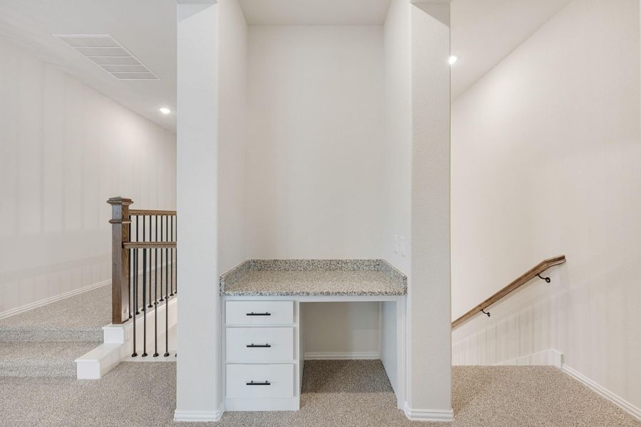 Built-in desk with granite top and white drawers in upstairs hallway near staircase railing Built-in desk with granite top and white drawers in upstairs hallway near staircase railing