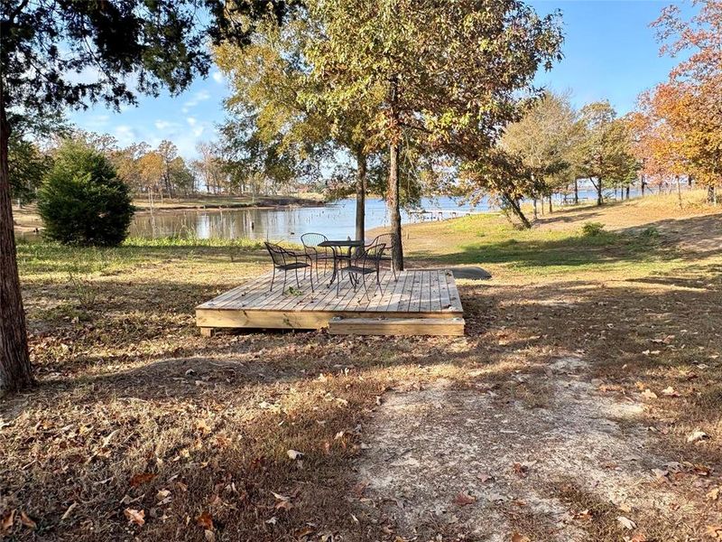 Surrounding community with a deck with water view and a yard