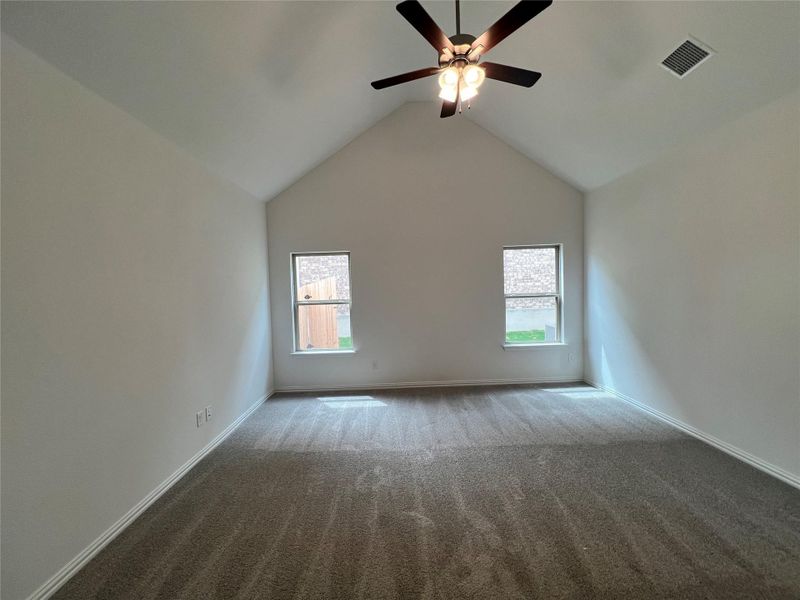 Empty room with carpet, ceiling fan, and vaulted ceiling Empty room with carpet, ceiling fan, and vaulted ceiling