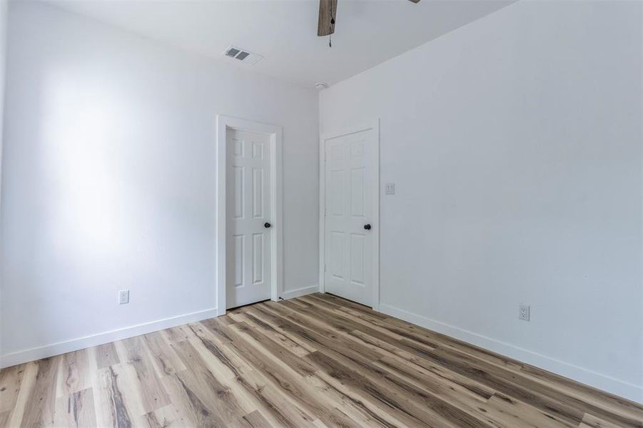 Empty room with light wood finished floors, a ceiling fan, and baseboards Empty room with light wood finished floors, a ceiling fan, and baseboards