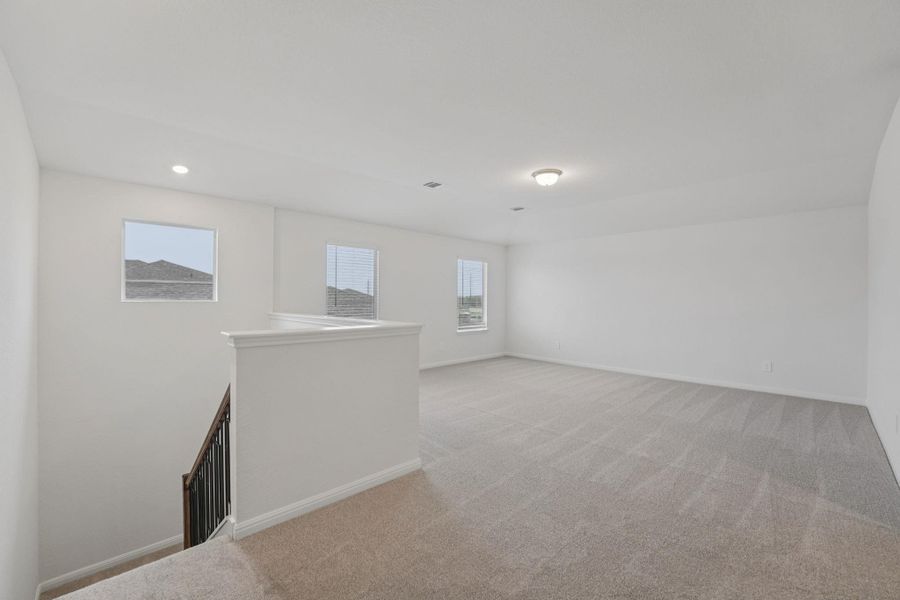 Empty room with light carpet and recessed lighting