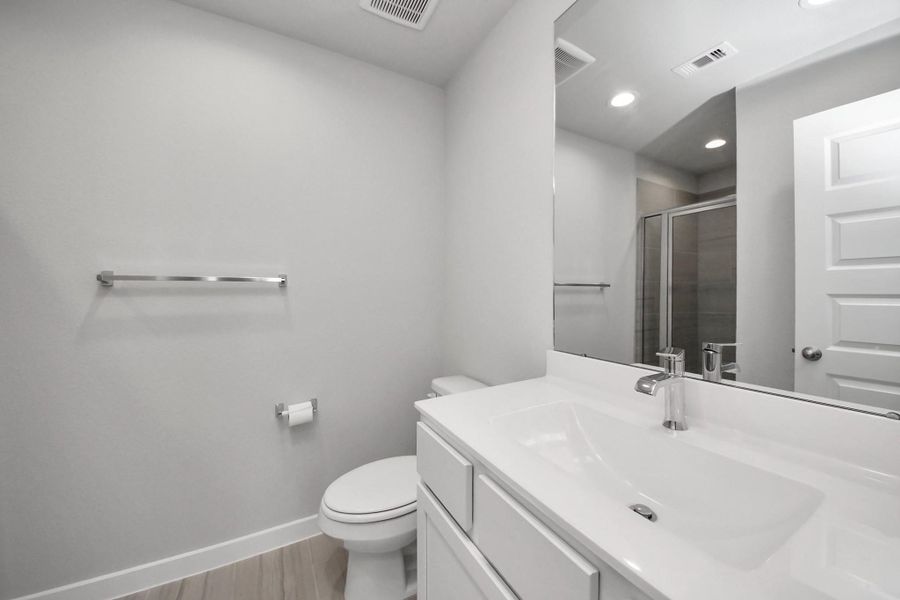 Private ensuite bathroom featuring a modern vanity, large mirror, and walk-in shower, serving as the home’s third full bathroom.