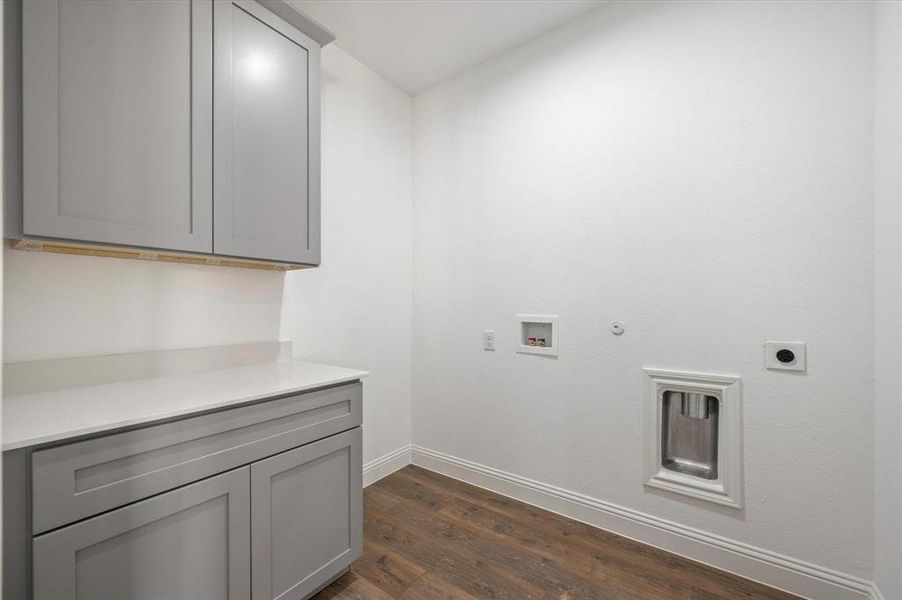 Clothes washing area featuring dark hardwood / wood-style flooring, gas dryer hookup, electric dryer hookup, washer hookup, and cabinets