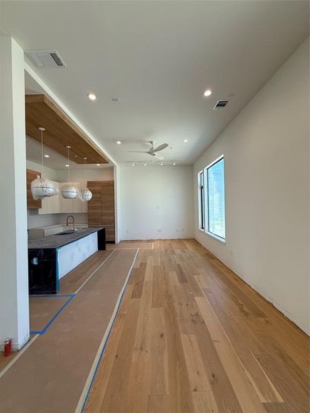 Unfurnished living room featuring light wood-style floors, a ceiling fan, and recessed lighting