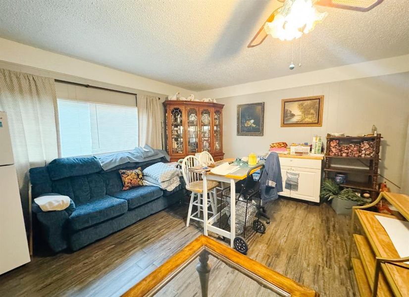 Home office with dark wood-type flooring, a textured ceiling, and ceiling fan