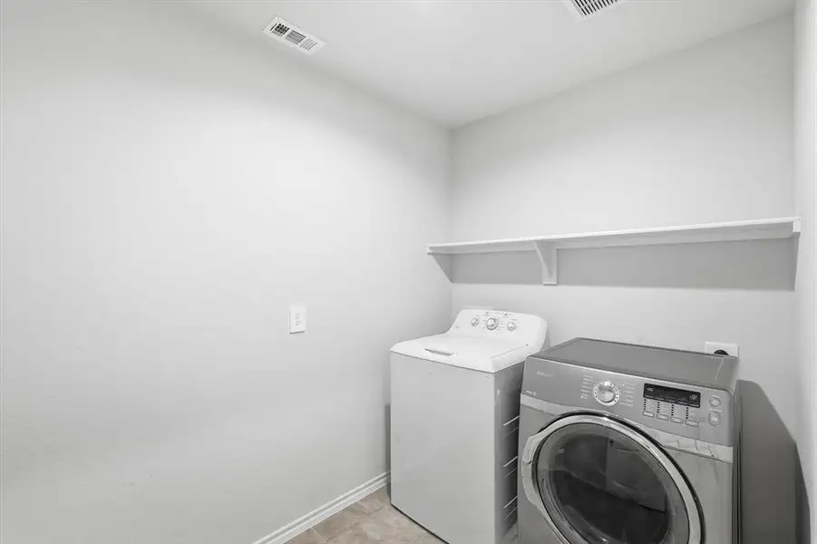 Laundry room with separate washer and dryer and light tile patterned flooring Laundry room with separate washer and dryer and light tile patterned flooring