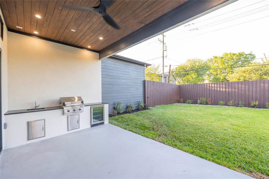 View of patio / terrace featuring beverage cooler, ceiling fan, area for grilling, sink, and a grill