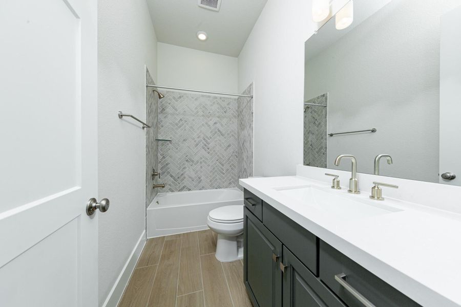 This well-appointed secondary bathroom offers exceptional functionality with its stained cabinet topped with pristine white quartz countertops and undermount sink. Sleek, polished fixtures complement the expansive vanity mirror and chic light vanity fixture. This well-appointed secondary bathroom offers exceptional functionality with its stained cabinet topped with pristine white quartz countertops and undermount sink. Sleek, polished fixtures complement the expansive vanity mirror and chic light vanity fixture.