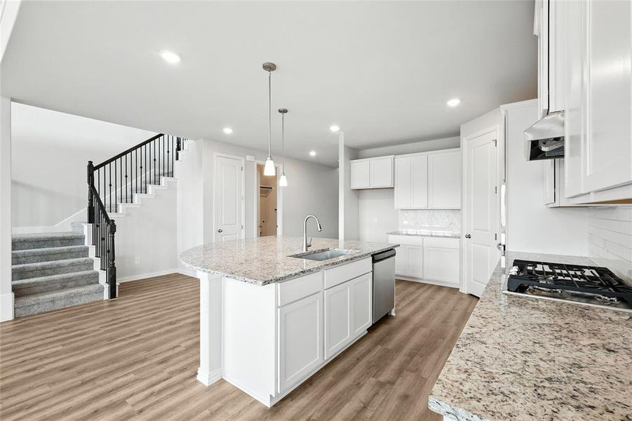 Kitchen featuring appliances with stainless steel finishes, light wood finished floors, decorative backsplash, range hood, and white cabinets Kitchen featuring appliances with stainless steel finishes, light wood finished floors, decorative backsplash, range hood, and white cabinets