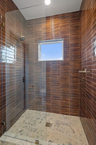 An inviting shower with distinctive brown tile walls and a clean glass enclosure.