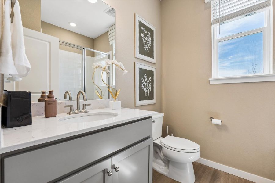 A bathroom with a sink toilet and mirror.