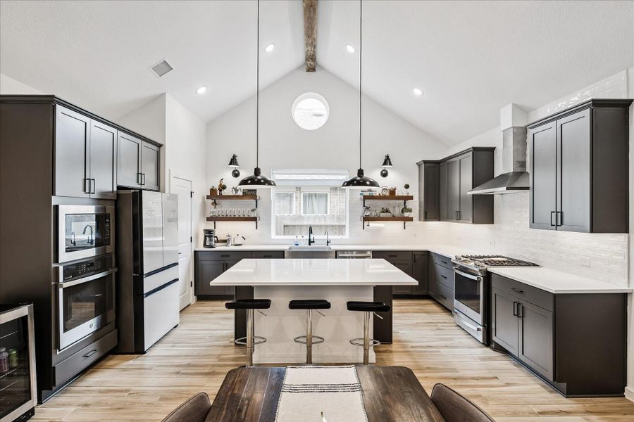 Chef-inspired kitchen featuring Carrara Morro quartz countertops, tile-to-ceiling backsplash, stainless steel appliances, farmhouse sink, and soft-close cabinetry.
