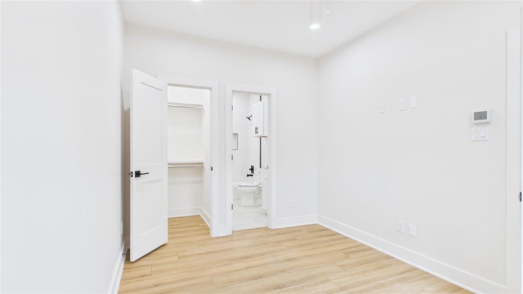 This photo showcases the first floor bedroom. The neutral walls and recessed lighting enhance the airy feel, making it a versatile space for any decor style.