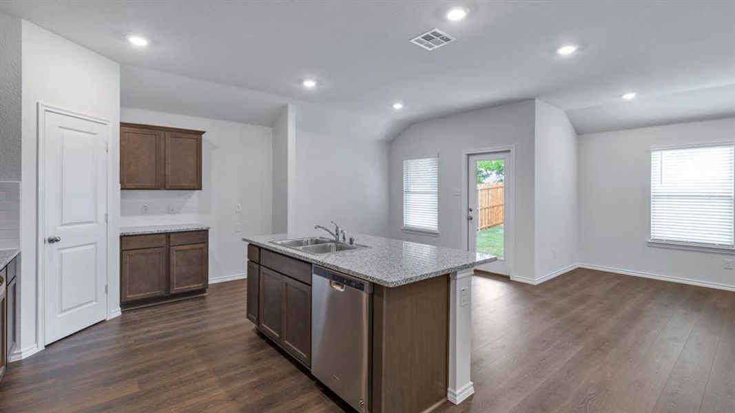 Kitchen featuring dishwasher, vaulted ceiling, dark wood-type flooring, a kitchen island with sink, and recessed lighting