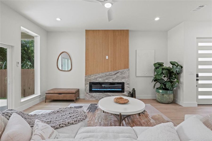 Living room featuring light hardwood / wood-style flooring, ceiling fan, and a high end fireplace