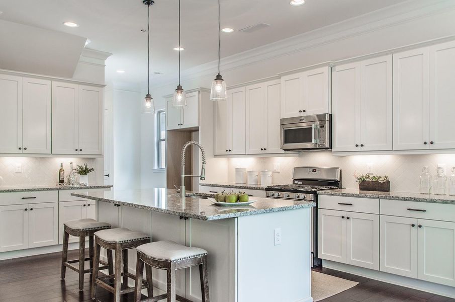 Kitchen featuring tasteful backsplash, dark wood-style flooring, appliances with stainless steel finishes, crown molding, and white cabinets Kitchen featuring tasteful backsplash, dark wood-style flooring, appliances with stainless steel finishes, crown molding, and white cabinets